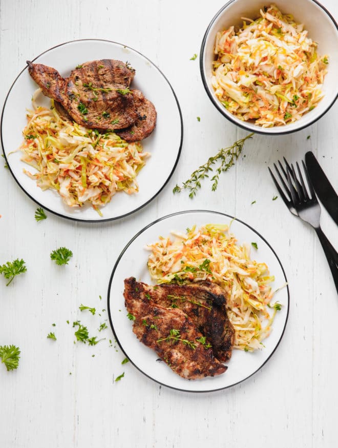 How To Cook Pork Shoulder Steak. Pork steaks on two white plates with side salad.