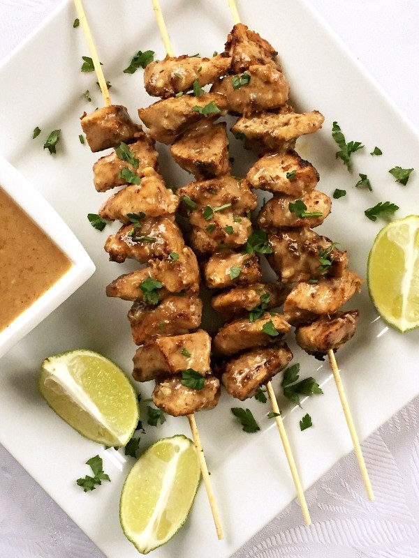 Overehead shoot of a white plate with chicken satay skewers