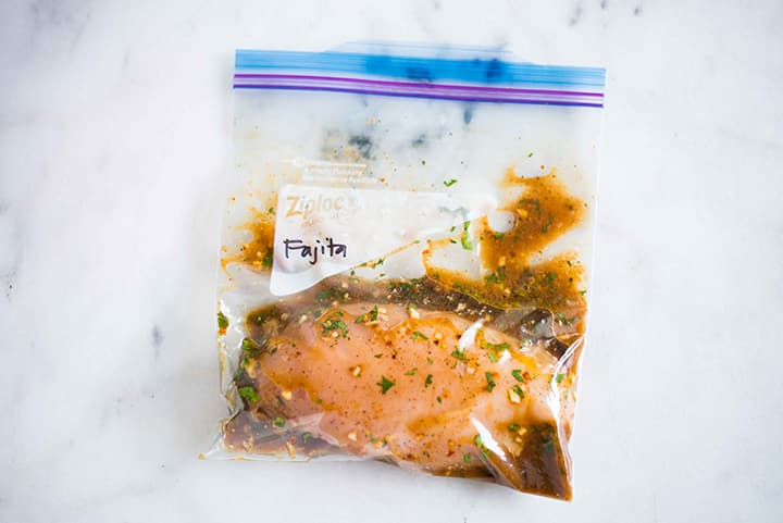 Sealable freezer bag with chicken breast and fajita chicken marinade, marinating and ready to cook.