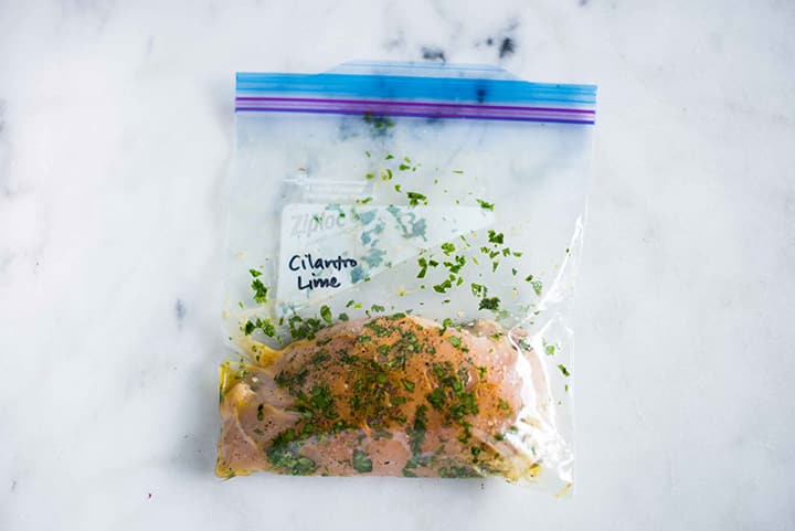 Bag with chicken breast and cilantro lime chicken marinade, marinating and ready to cook.